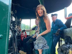 Happy woman with shovel of coal ready to add fuel to the steam engine